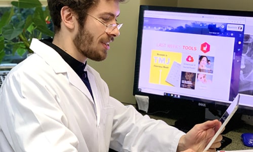 A dentist who is wearing glasses using Roadside's online reputation management platform on his tablet
