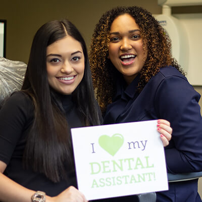 Dental office workers holding social sign