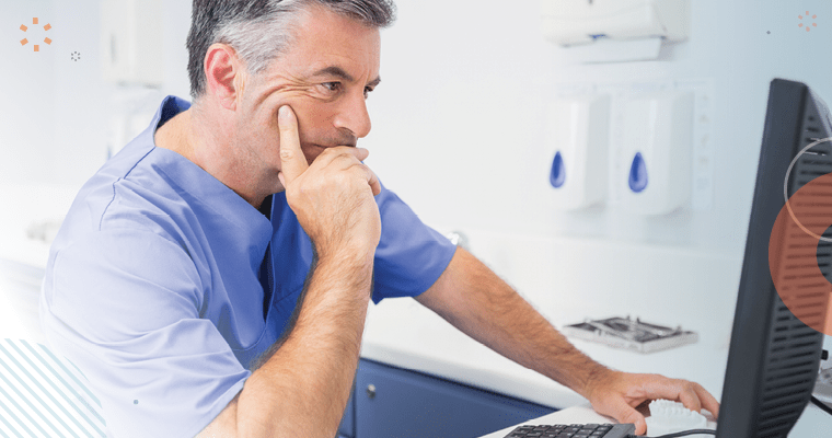 An overwhelmed dentist looking at his computer and dealing with a staffing shortage